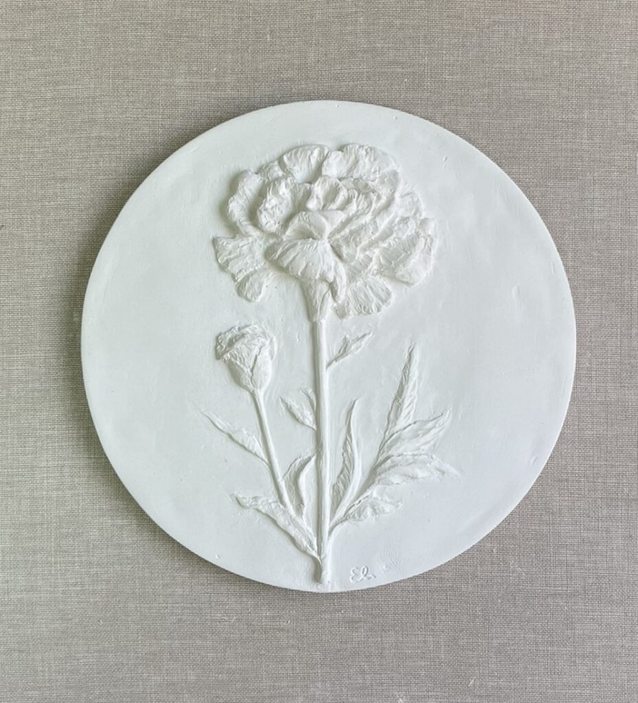 Relieve blanco de un clavel en escayola, obra escultórica de temática floral sobre arte botánico
